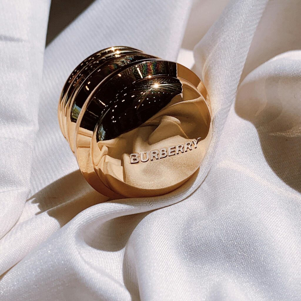 Luxurious Burberry perfume bottle resting on white silk fabric, showcasing elegance and style.