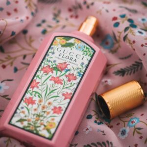 A stylish Gucci Flora perfume bottle on floral fabric, showcasing luxury and elegance.