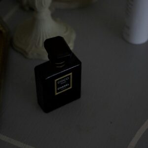 Chic black perfume bottle on a vintage grey table setting, exuding luxury.