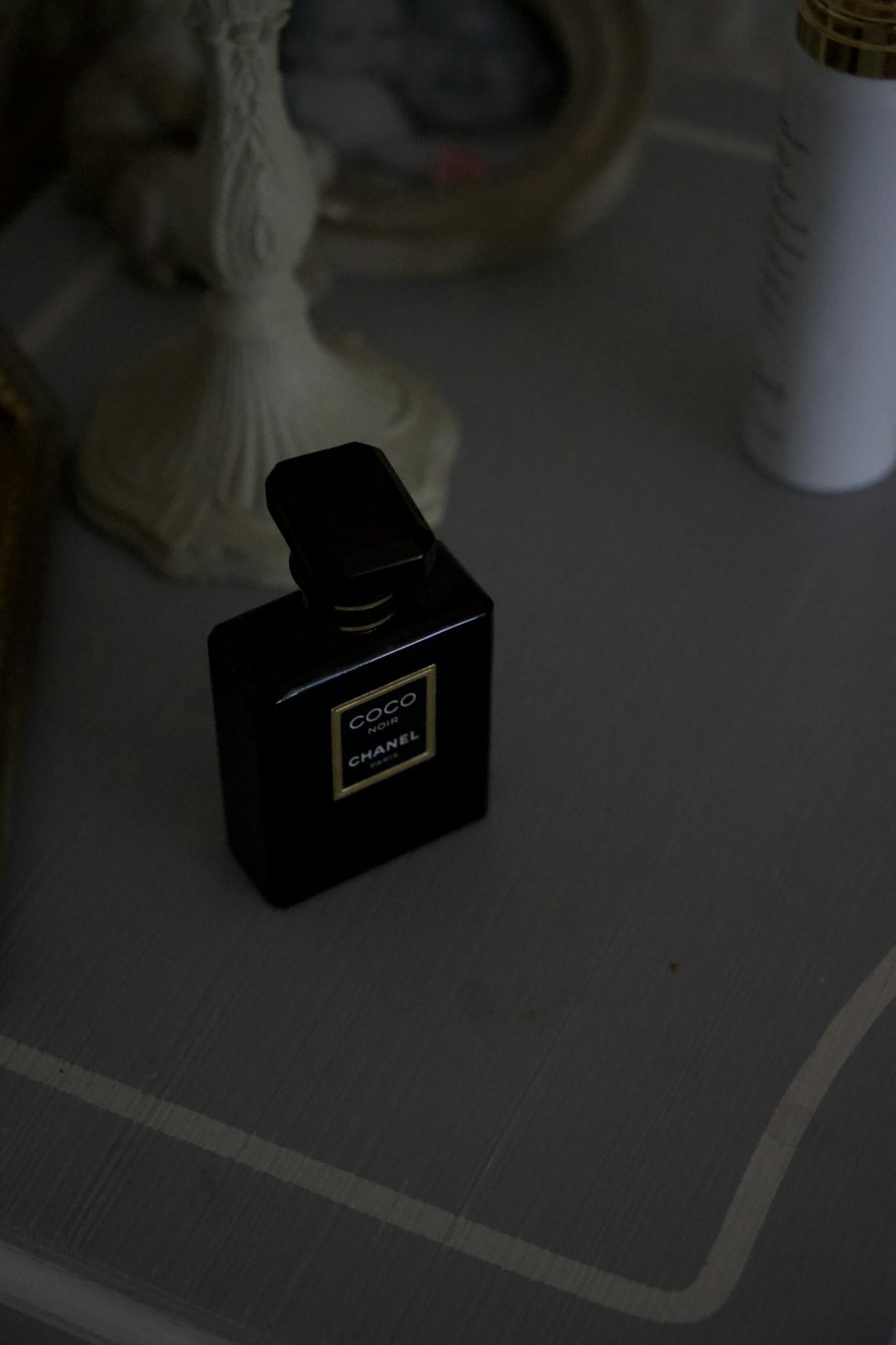 Chic black perfume bottle on a vintage grey table setting, exuding luxury.