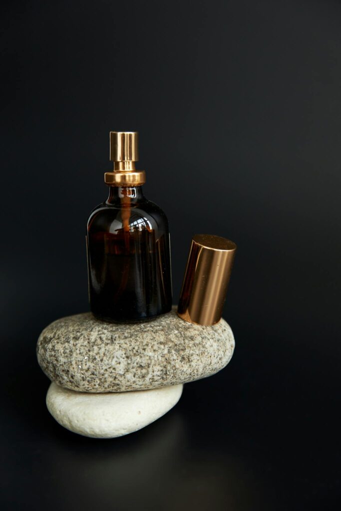Close-up of a perfume bottle on stones with a black background.