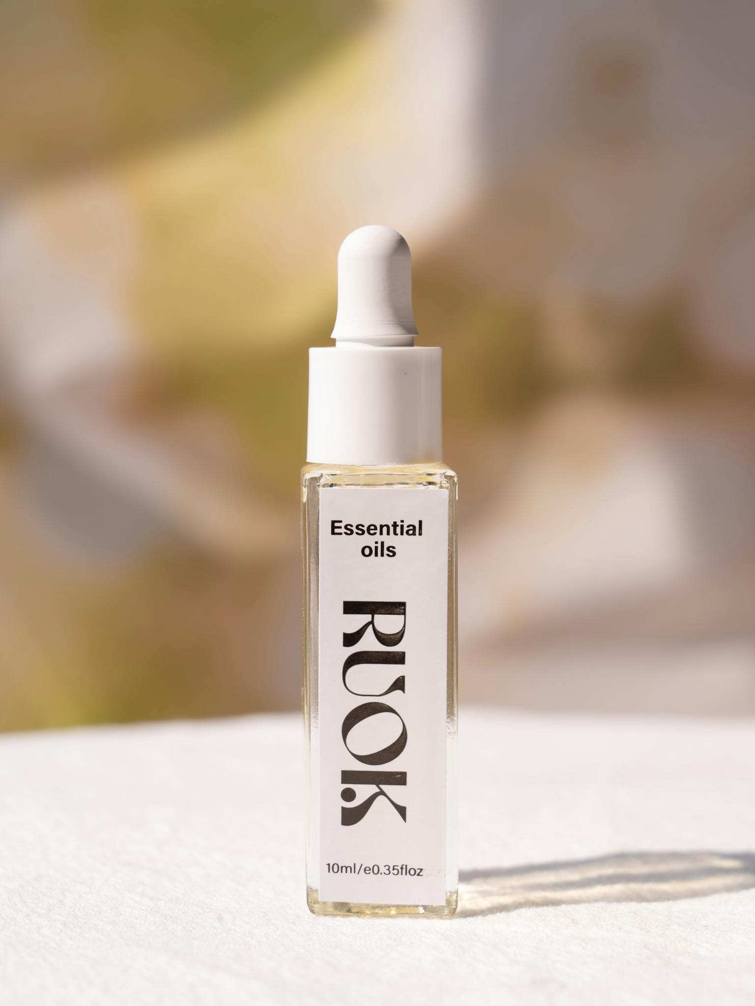 Elegant essential oil dropper bottle against a neutral background.
