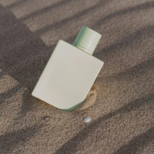 Elegant minimalist perfume bottle set against textured sand background.