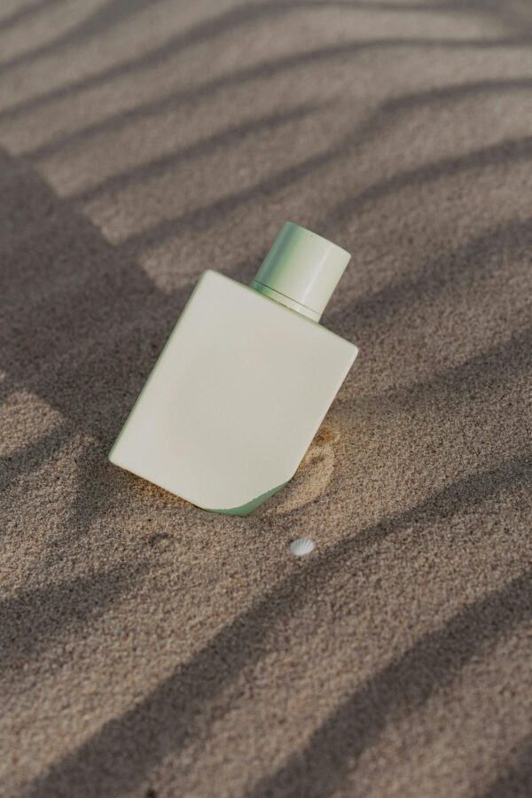 Elegant minimalist perfume bottle set against textured sand background.