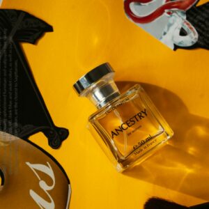 Top view of bottle of perfume placed on yellow surface near magazine clippings in daylight